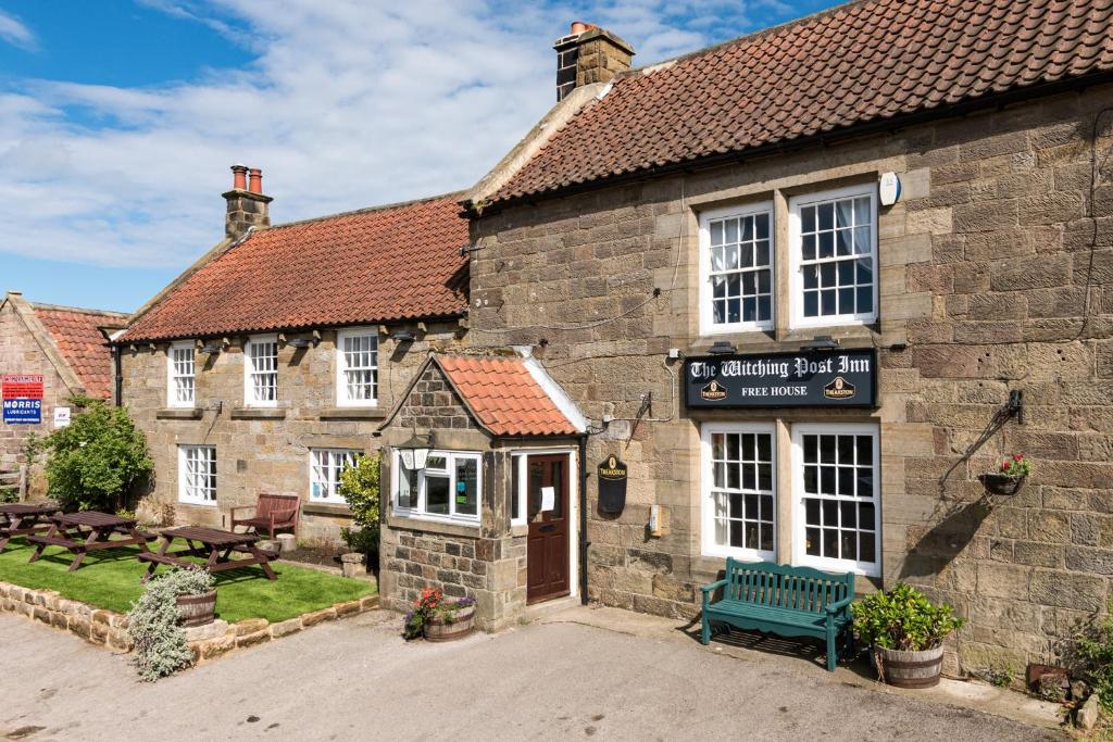 un vieux bâtiment en briques avec un banc devant lui dans l'établissement The Witching Post Inn, à Whitby