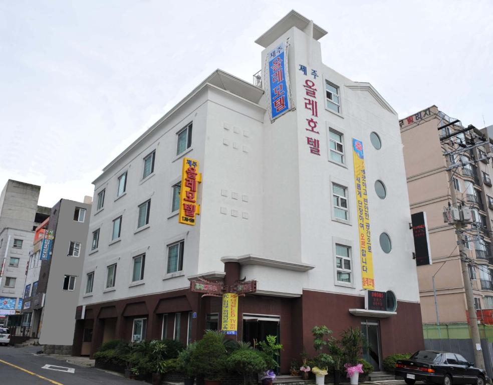 a white building with signs on the side of it at Jeju Olleh Hotel in Jeju