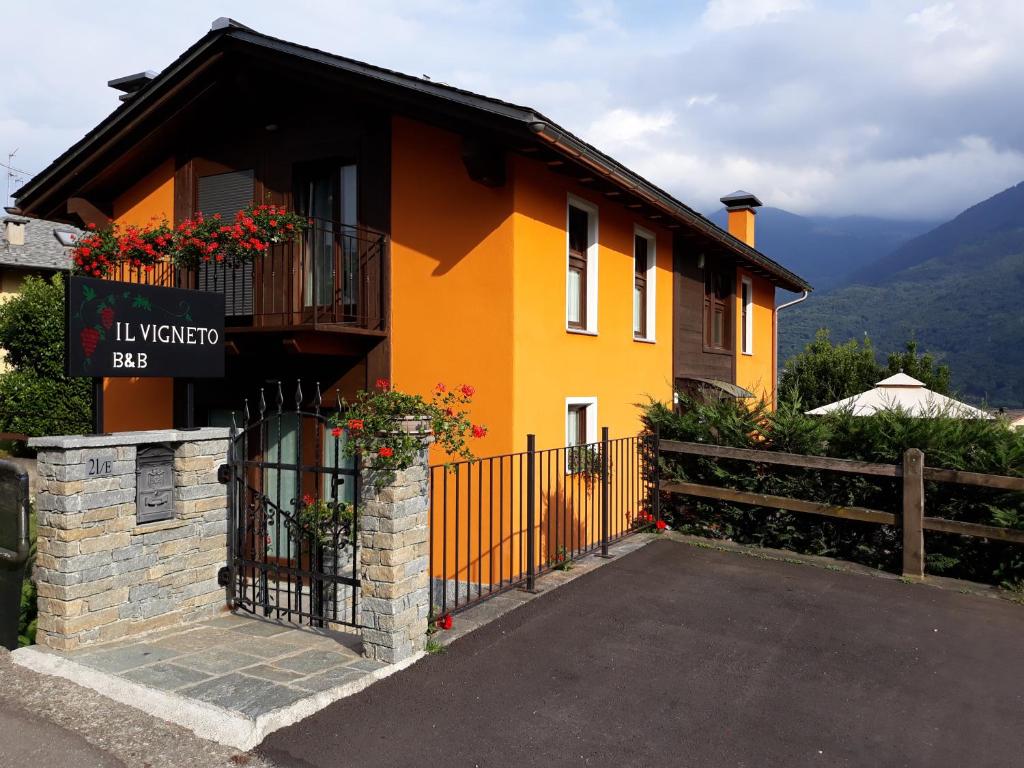 żółty dom z balkonem i ogrodzeniem w obiekcie Il Vigneto w mieście Castione Andevenno