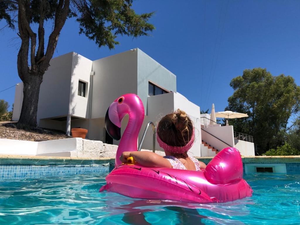 a woman riding a pink flamingo in a pool at Made iN2 Creative Guest House in Montargil