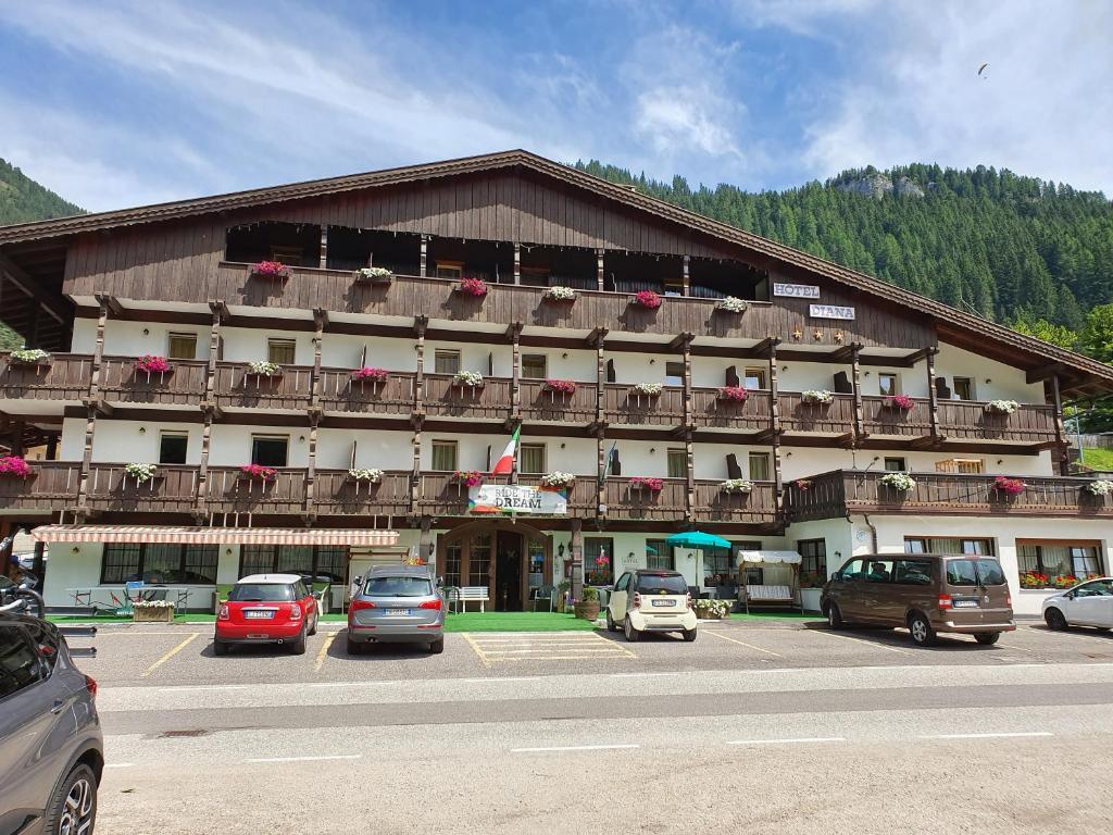 duży budynek z samochodami zaparkowanymi na parkingu w obiekcie Hotel Diana w mieście Canazei