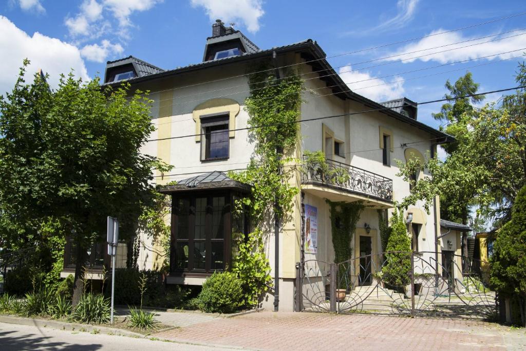 an old white house with a balcony on a street at Oberża Złota Gęś in Siewierz