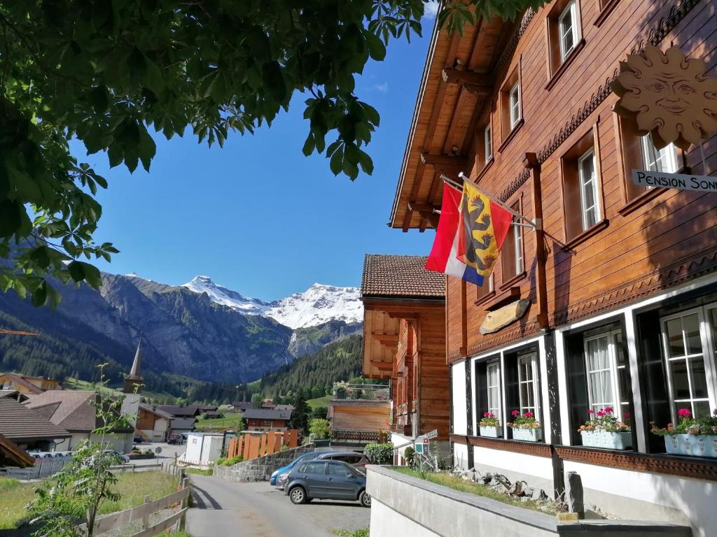 une ville dans les montagnes avec drapeau sur un bâtiment dans l'établissement Pension Sonne, à Adelboden