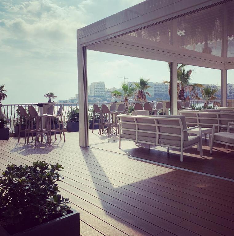 a wooden deck with chairs and tables on a balcony at Cavalieri Art Hotel in St. Julianʼs