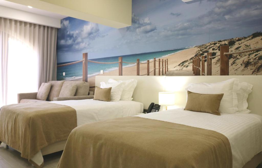 two beds in a room with a mural of a beach at Lagos Atlantic Hotel in Lagos