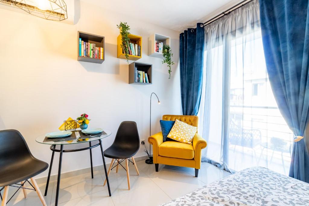 a bedroom with a yellow chair and a table at Light House - Seafront cosy studio with library in Paphos City