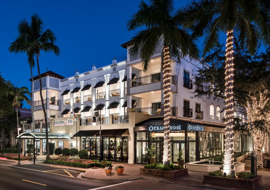 a large white building with palm trees in front of it at Inn On Fifth in Naples