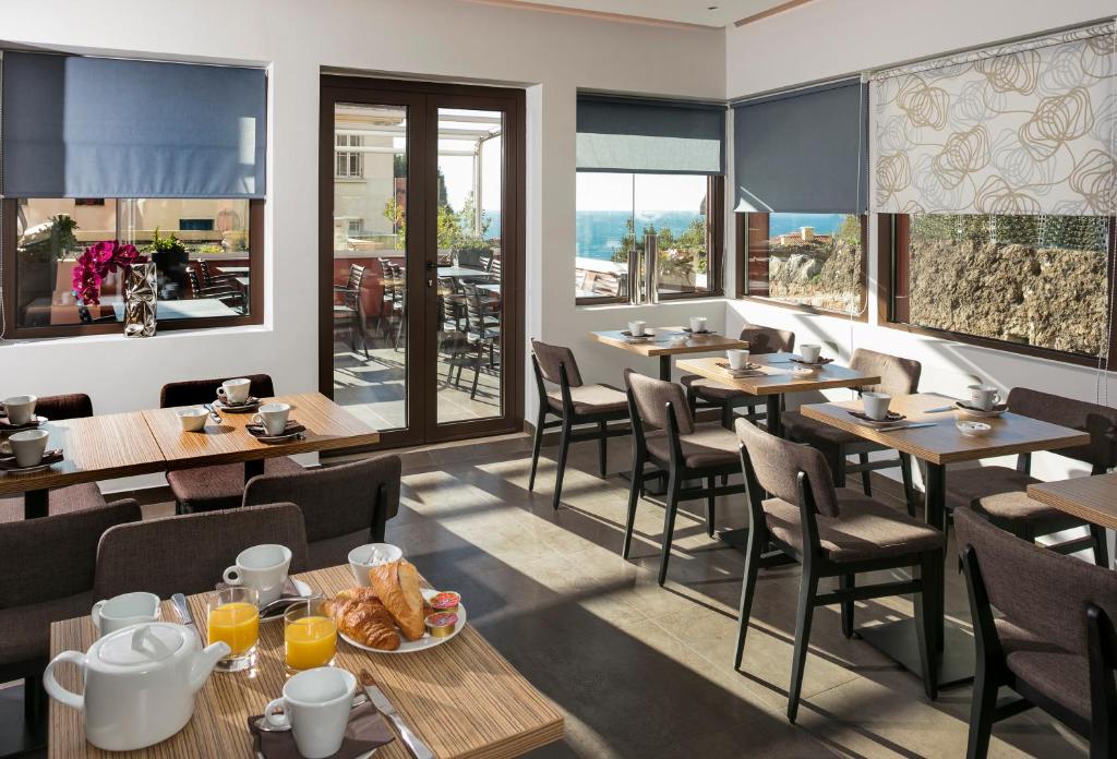 a restaurant with wooden tables and chairs and windows at Hotel Miramar in Cap d'Ail