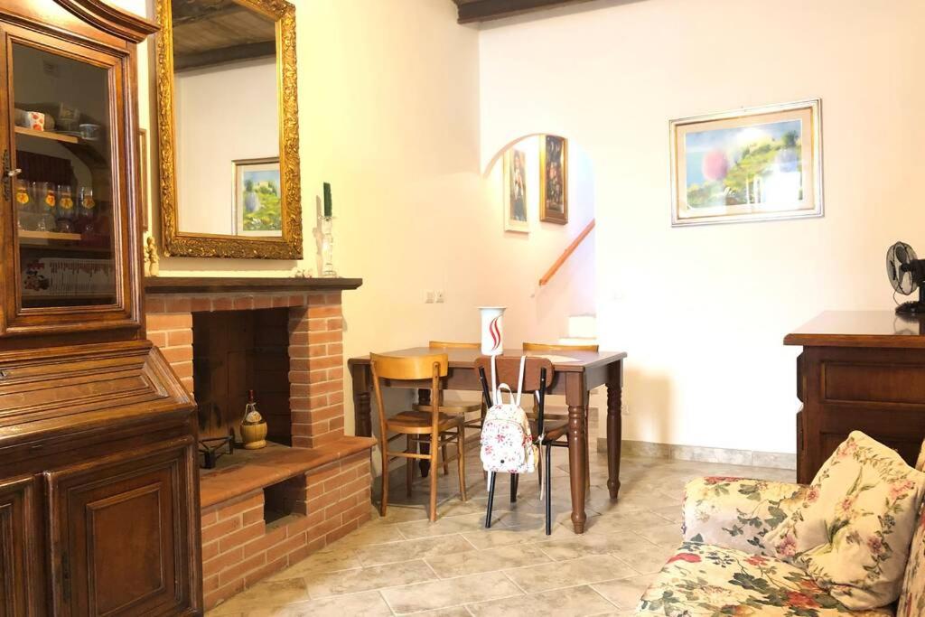 sala de estar con chimenea, mesa y espejo en Casa Profumo d' Estate, en Pitigliano