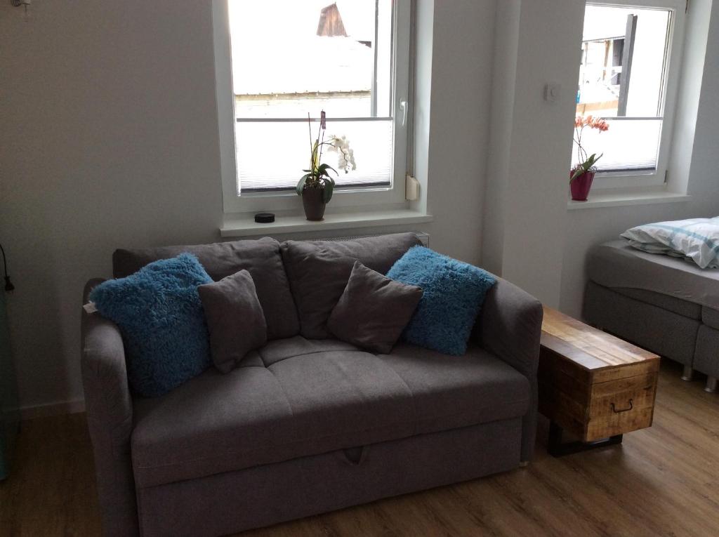 ein Sofa im Wohnzimmer mit zwei Fenstern in der Unterkunft Fewo Eifeler Edelsteine „Aquamarin“ in Schleiden