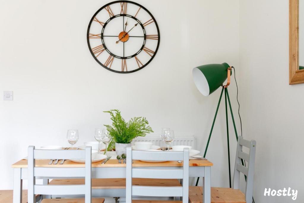 uma sala de jantar com uma mesa e um relógio na parede em Albatross House - Comfy Home with Parking em Slough
