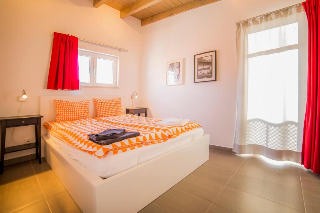a bedroom with a bed and a window with red curtains at Apartamentos Marreiros Neto in Lagos