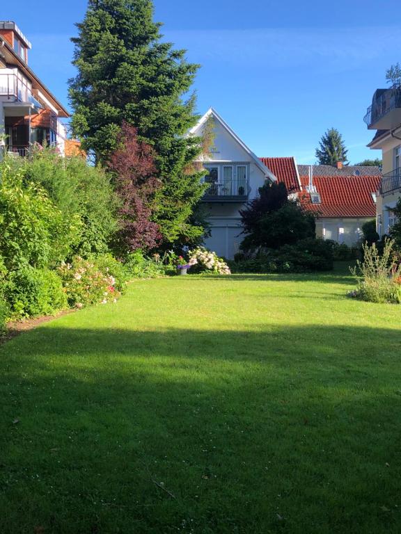 einen Hof mit grünem Rasen mit einem Baum und Häusern in der Unterkunft Villa Senator-Marstall in Travemünde