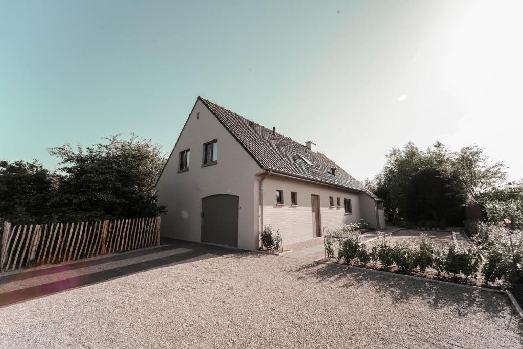 une maison blanche avec un portail et une allée. dans l'établissement Villa Arleo, à Nieuport