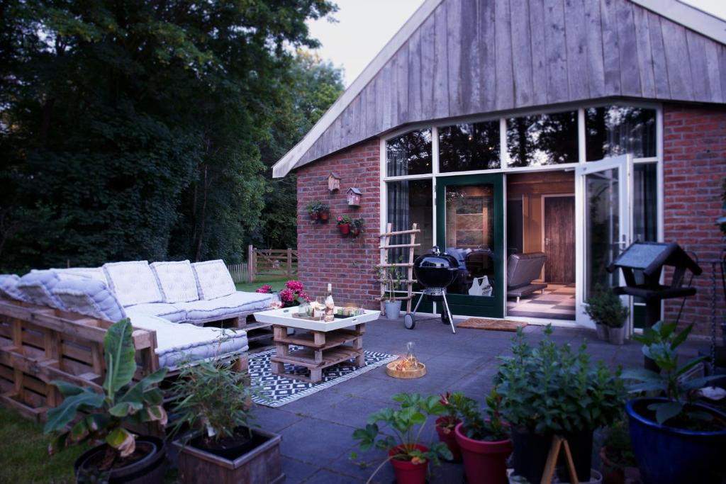 eine Terrasse mit einem Sofa und einem Tisch vor einem Gebäude in der Unterkunft Buitenverblijf Het Grootenhuis in Winterswijk Henxel