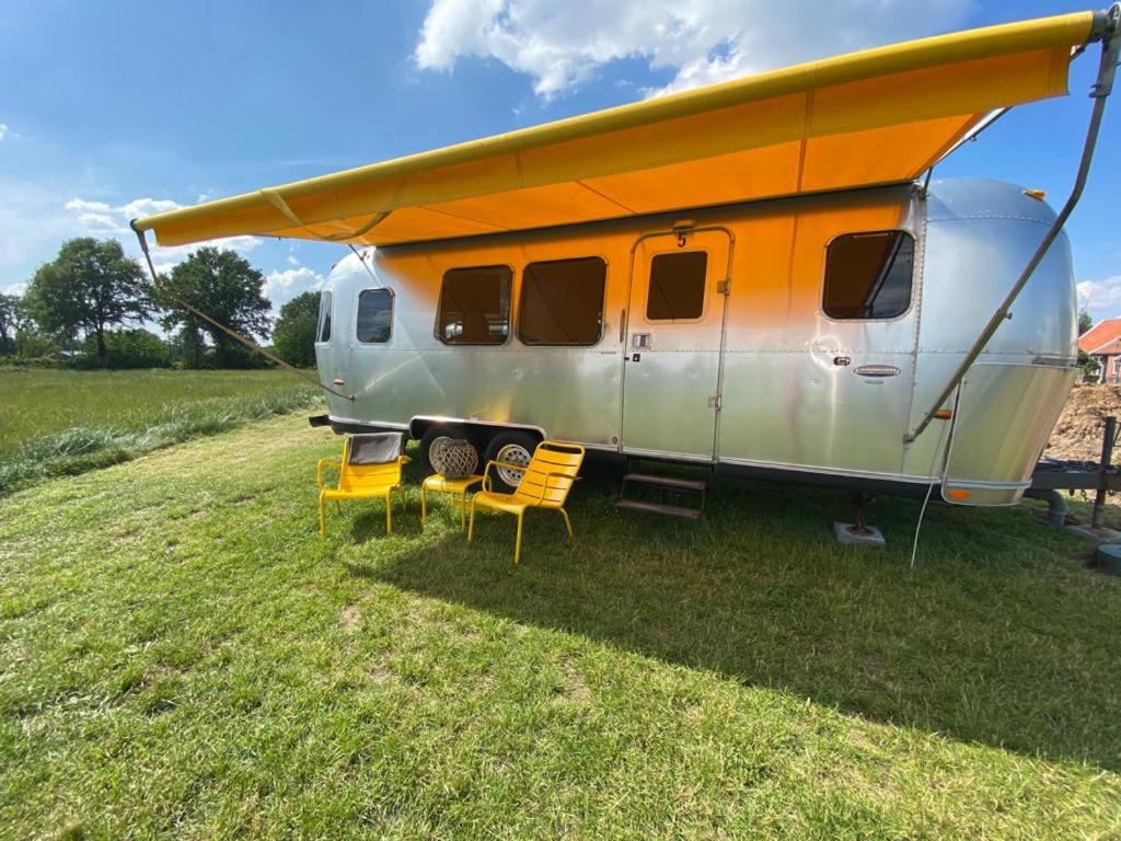 een camper met een oranje dak geparkeerd in een veld bij Amerikaanse Airstream voor 2 personen in Reutum