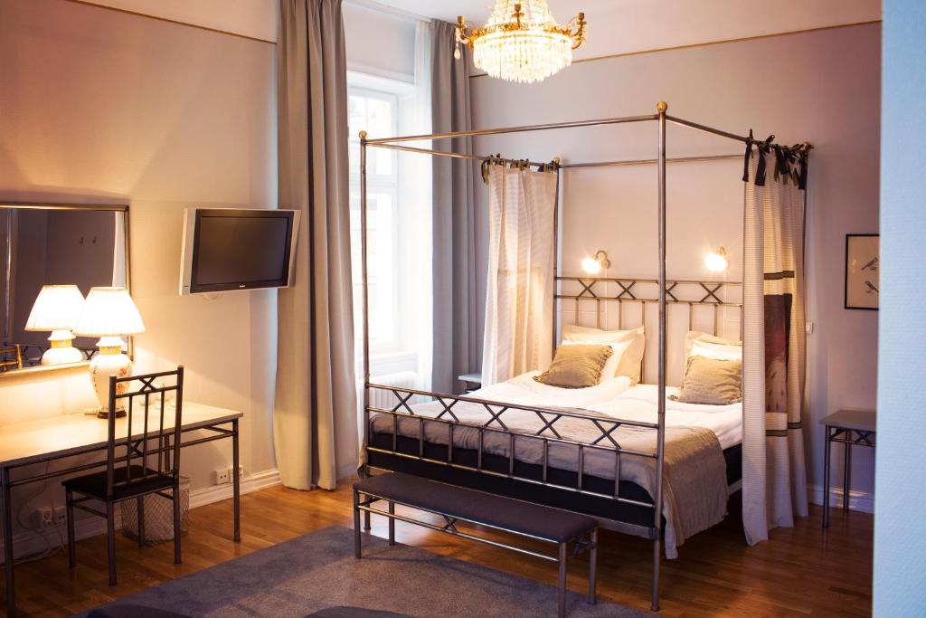 a bedroom with a four poster bed and a desk at Grand Hotell Hörnan in Uppsala