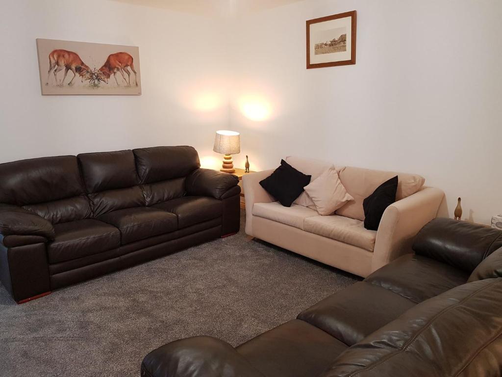 a living room with two leather couches and a couch at Pleasant Point Holiday Cottages in Rosemarkie