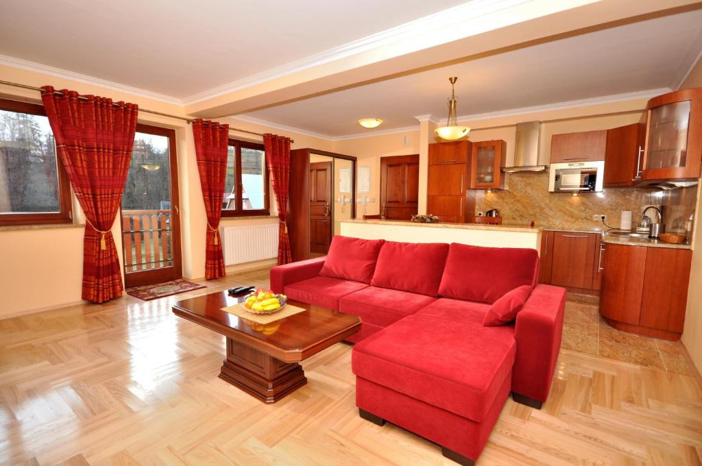a living room with a red couch and a table at Apartament Plumeria in Zakopane