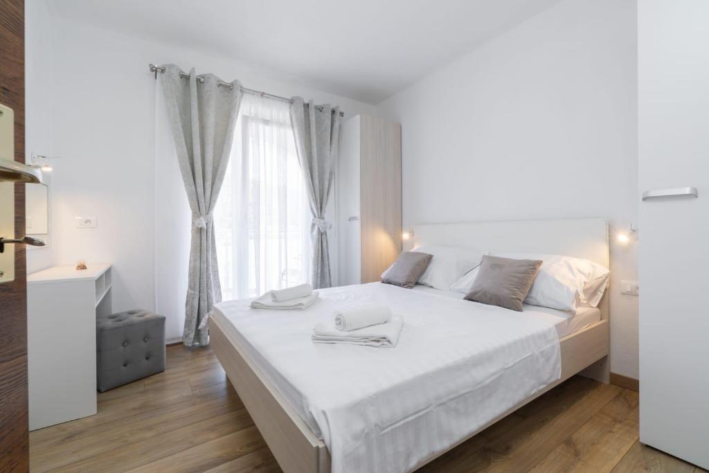 Un dormitorio blanco con una gran cama blanca y una ventana en MALOA two bedroom apartment, en Smokvica