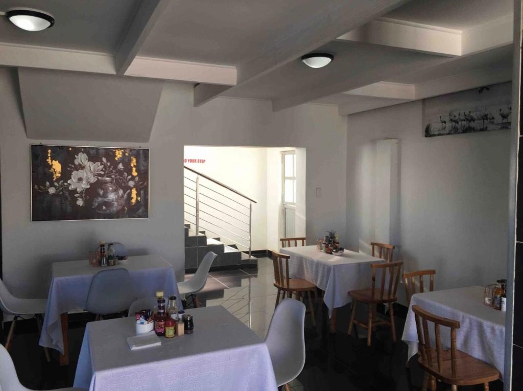 a restaurant with white tables and chairs and a staircase at White House lodge in Mthatha