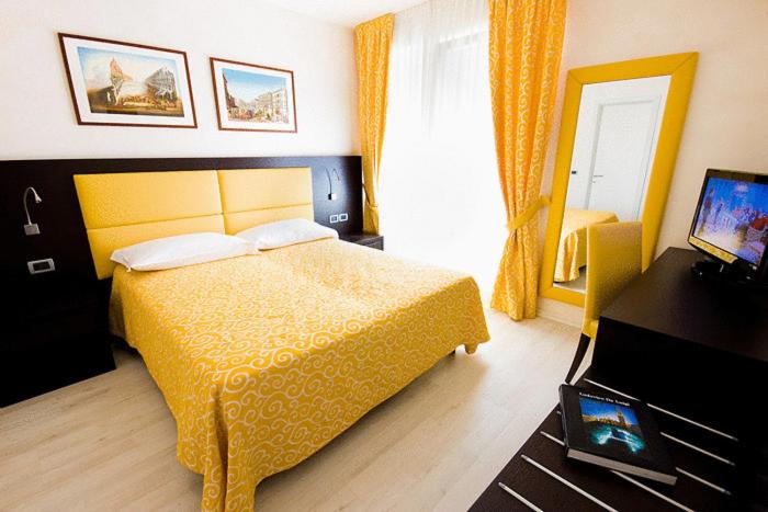 una camera con letto giallo e televisore di Hotel La Pergola di Venezia a Lido di Venezia