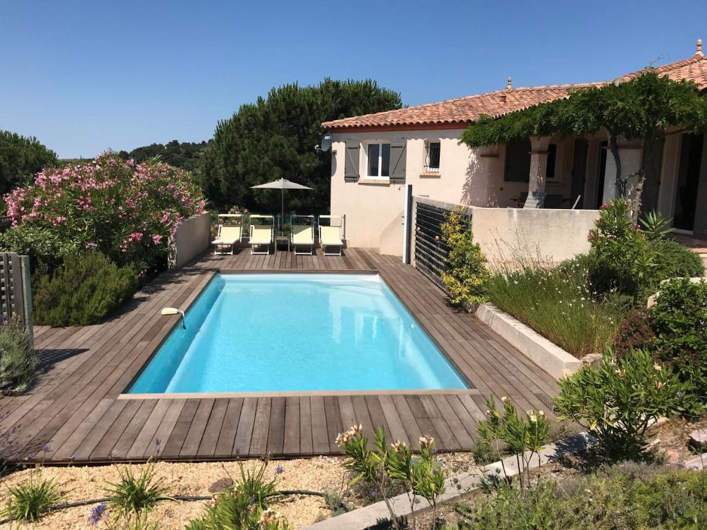 einen Pool in einem Garten mit einer Holzterrasse in der Unterkunft Cozy Villa in Caunes Minervois with Swimming Pool in Caunes-Minervois