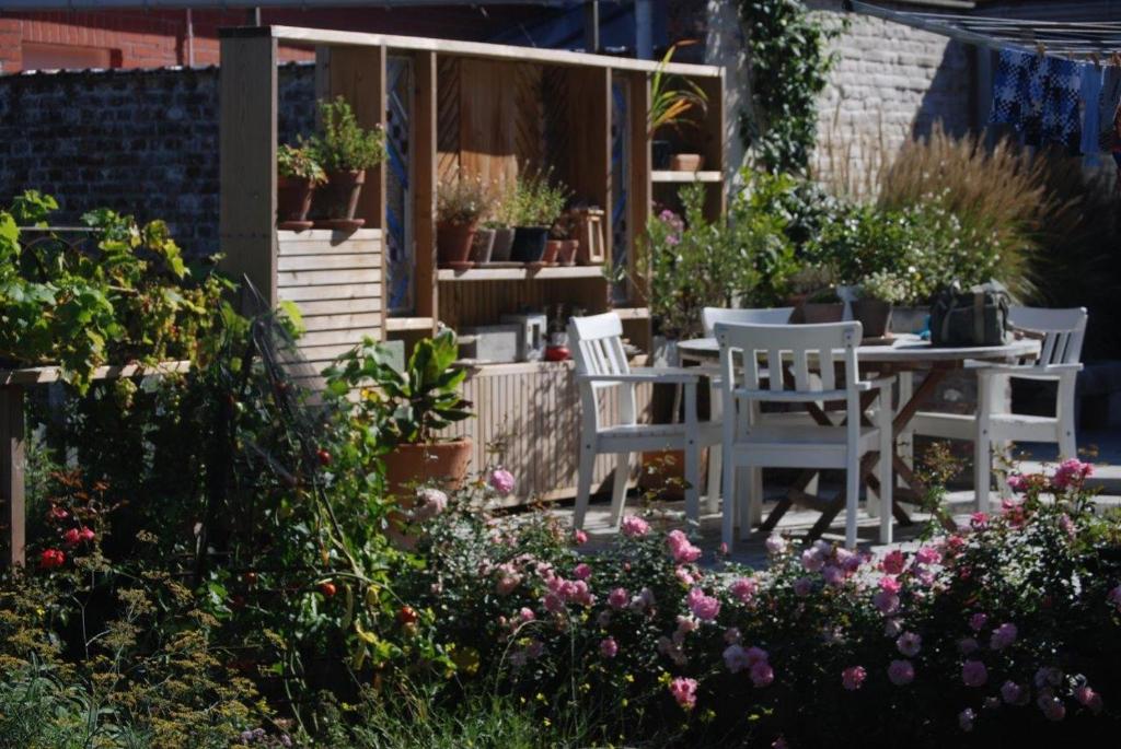 un patio con tavolo, sedie e fiori di Het Oud Schoolmeesterhuis a Watou