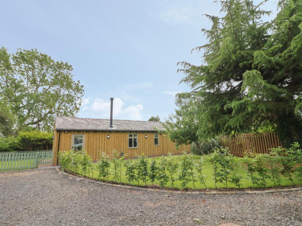 uma casa de madeira com uma cerca e um jardim em The Hen House em Rugeley