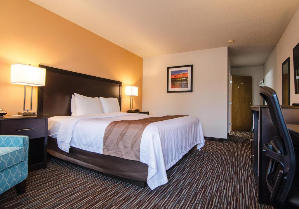 a hotel room with a large bed and a chair at Cottage Grove Inn in Cottage Grove