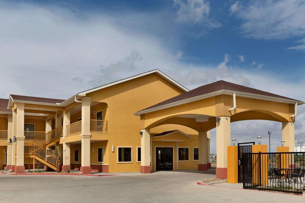 a large yellow building with a parking lot at Days Inn by Wyndham Odessa in Odessa