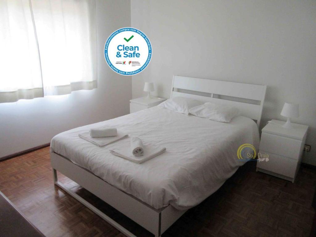 ペニシェにあるSol e Praia - Peniche IIIの白いベッド(清潔で安全なサイン付)が備わるベッドルームのベッド1台