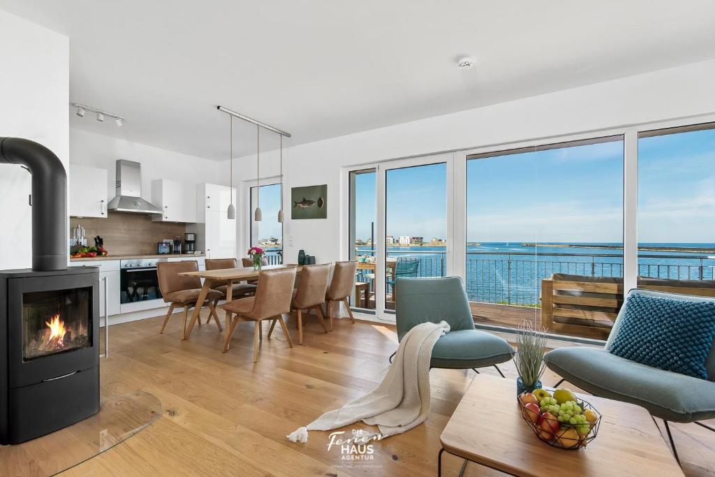 a living room with a fireplace and a view of the ocean at Perlentaucher in Olpenitz