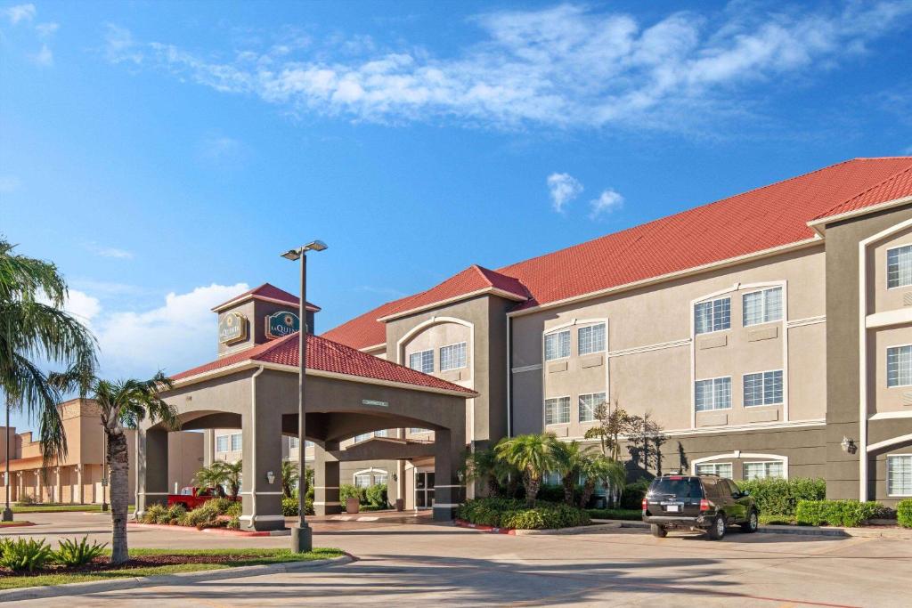 a hotel with a clock tower in a parking lot at La Quinta by Wyndham Mercedes in Mercedes