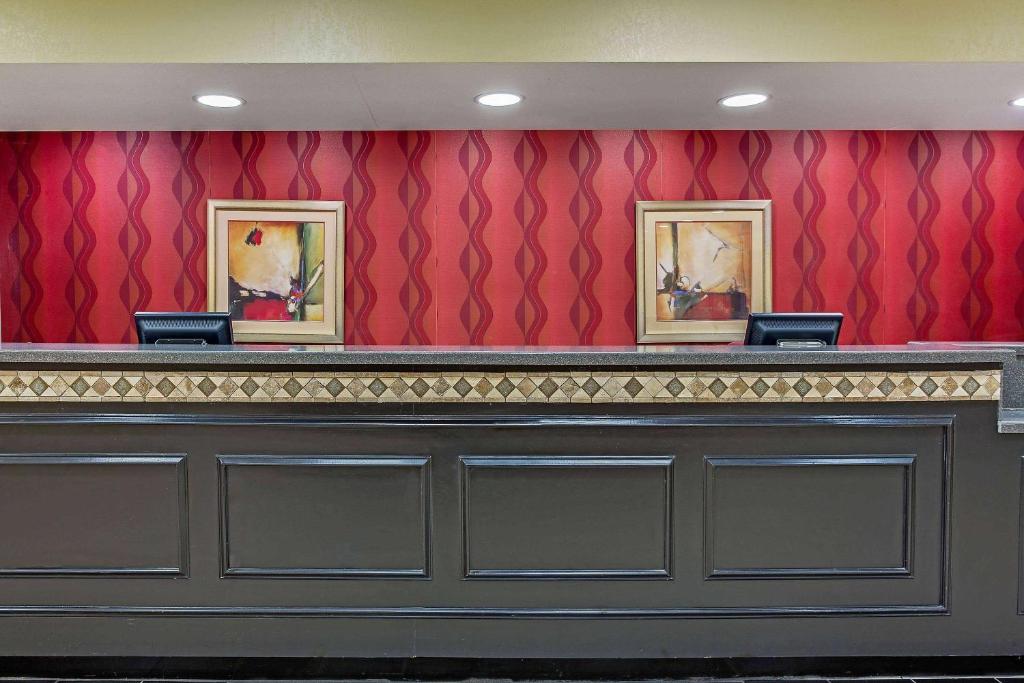 un bar avec deux peintures sur un mur rouge dans l'établissement La Quinta by Wyndham Canton MS, à Canton