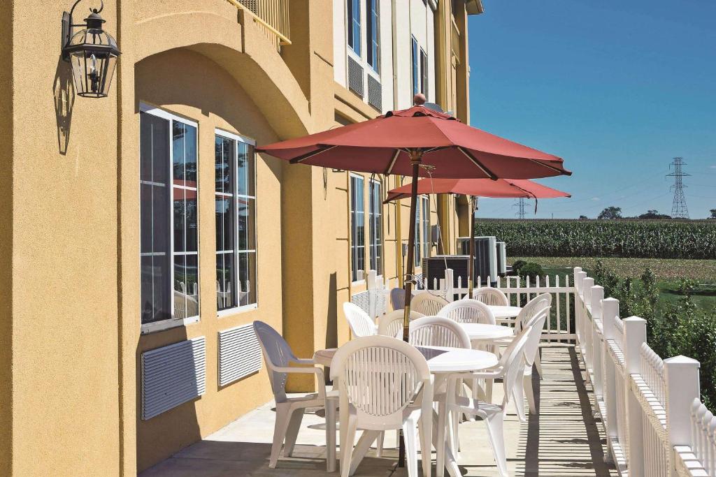 a row of tables and chairs with a red umbrella at La Quinta by Wyndham Lancaster in Ronks