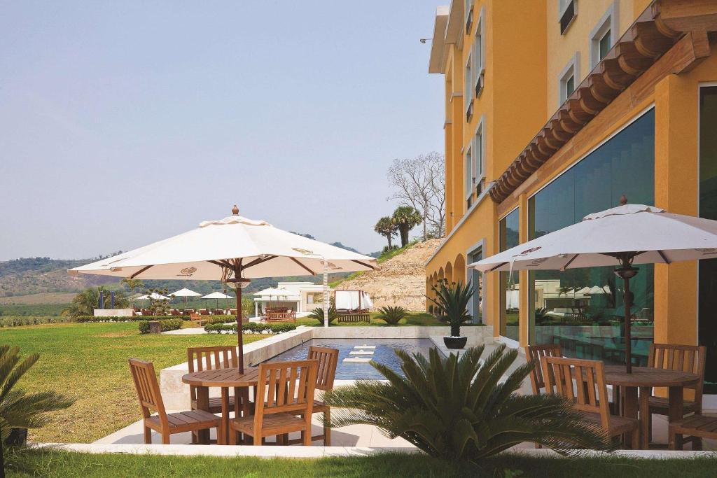 un patio avec des tables et des parasols à côté d'un bâtiment dans l'établissement La Quinta by Wyndham Poza Rica, à Poza Rica de Hidalgo