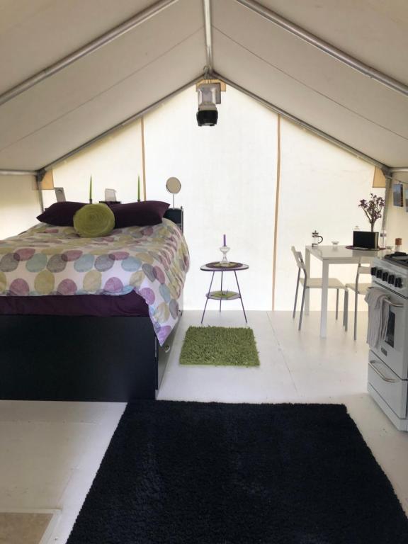 - une chambre dans une tente avec un lit et une table dans l'établissement Vines and Puppies Glamping Hideaway, à Jade City