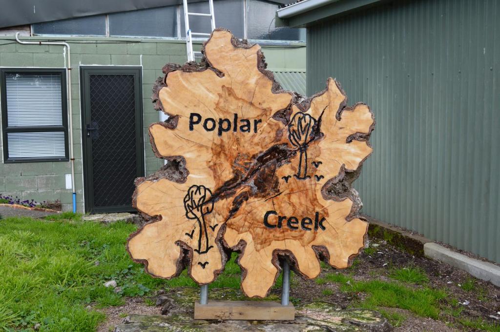 a wooden sign that says poplar creek at Poplar Creek B&B in Matamata