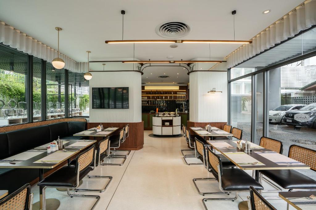 a dining room with tables and chairs and windows at Hotel Amber Sukhumvit 85 in Bangkok