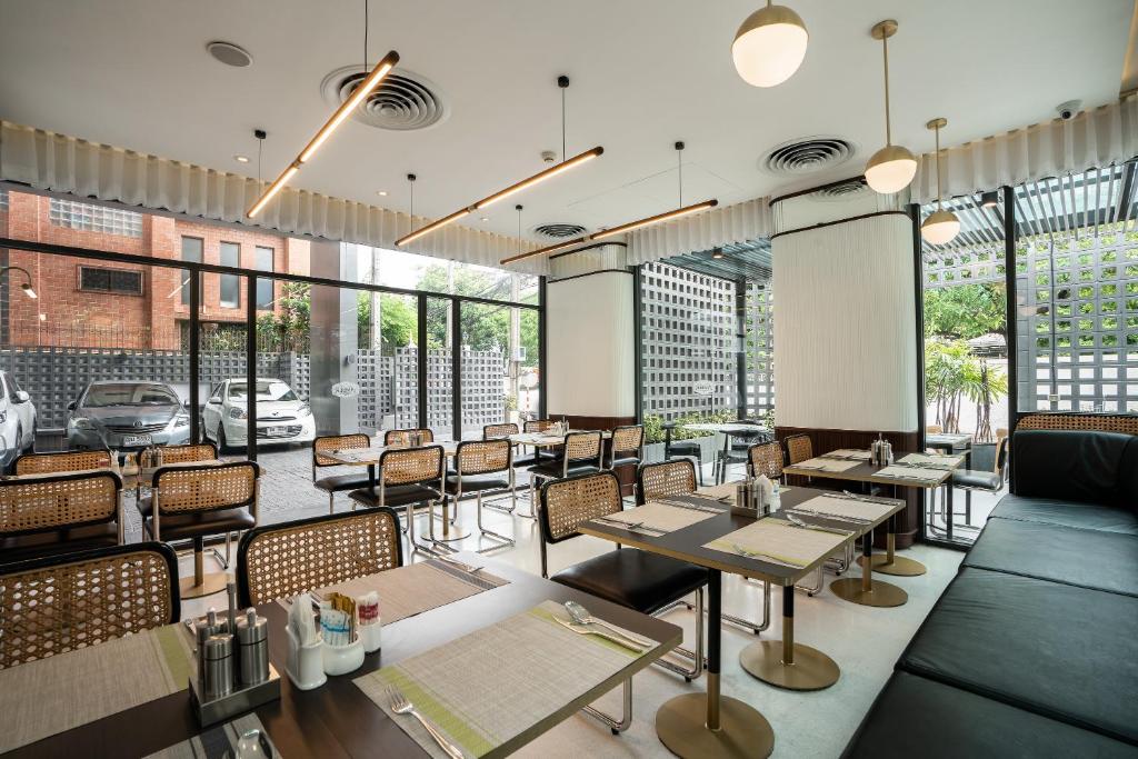 a restaurant with tables and chairs and windows at Hotel Amber Sukhumvit 85 in Bangkok