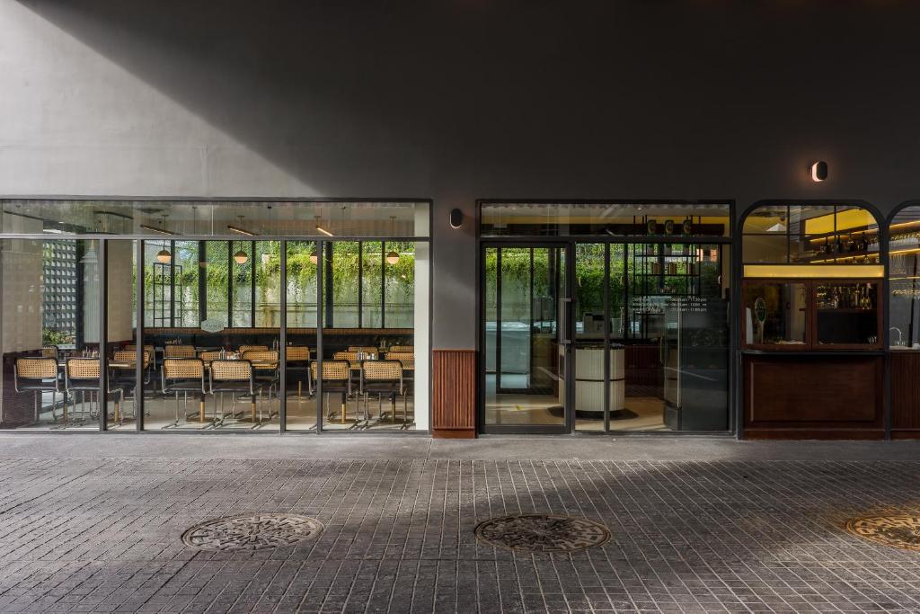a building with glass doors with tables and chairs at Hotel Amber Sukhumvit 85 in Bangkok