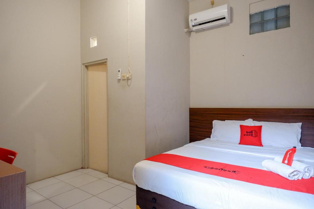Dormitorio pequeño con cama con almohada roja en RedDoorz near Stasiun Tawang Semarang en Semarang