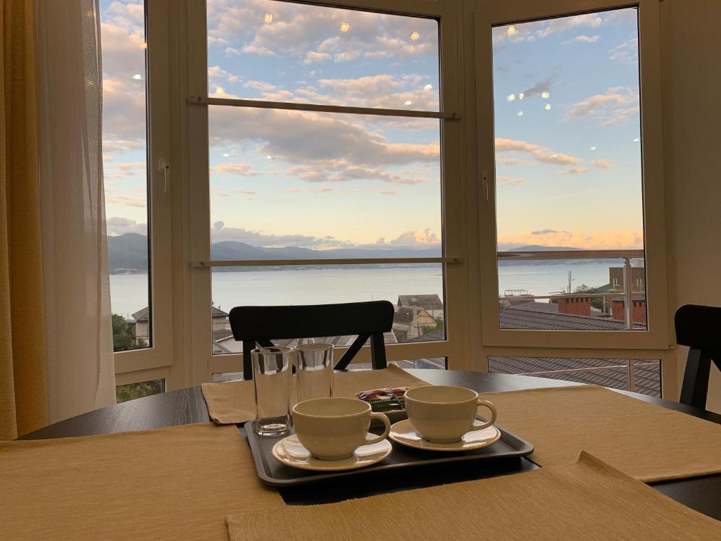 una mesa con dos tazas y una bandeja con vistas en Sunny Harbour, en Novorossiysk