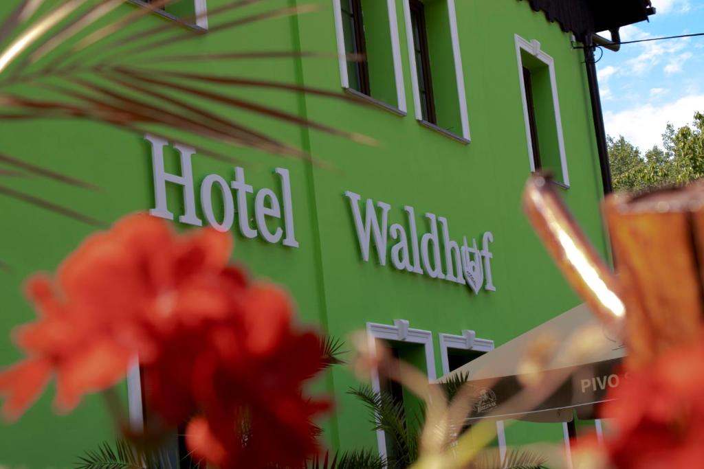 Jiříkov的住宿－Waldhof，一座绿色的酒店建筑,前面有红花