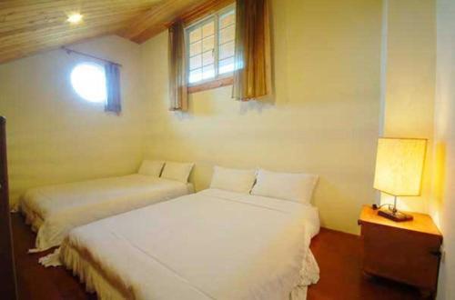 a bedroom with two white beds and a window at Euro Country Villa in Ren&#39;ai