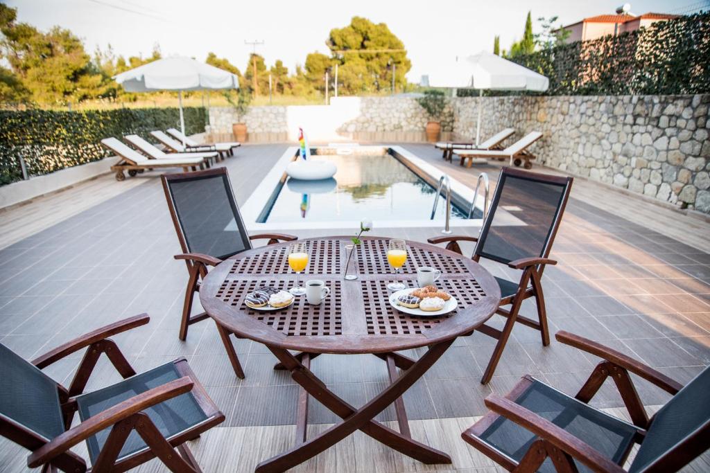 a wooden table and chairs on a patio with a pool at Private pool Sani villa in Sani Beach