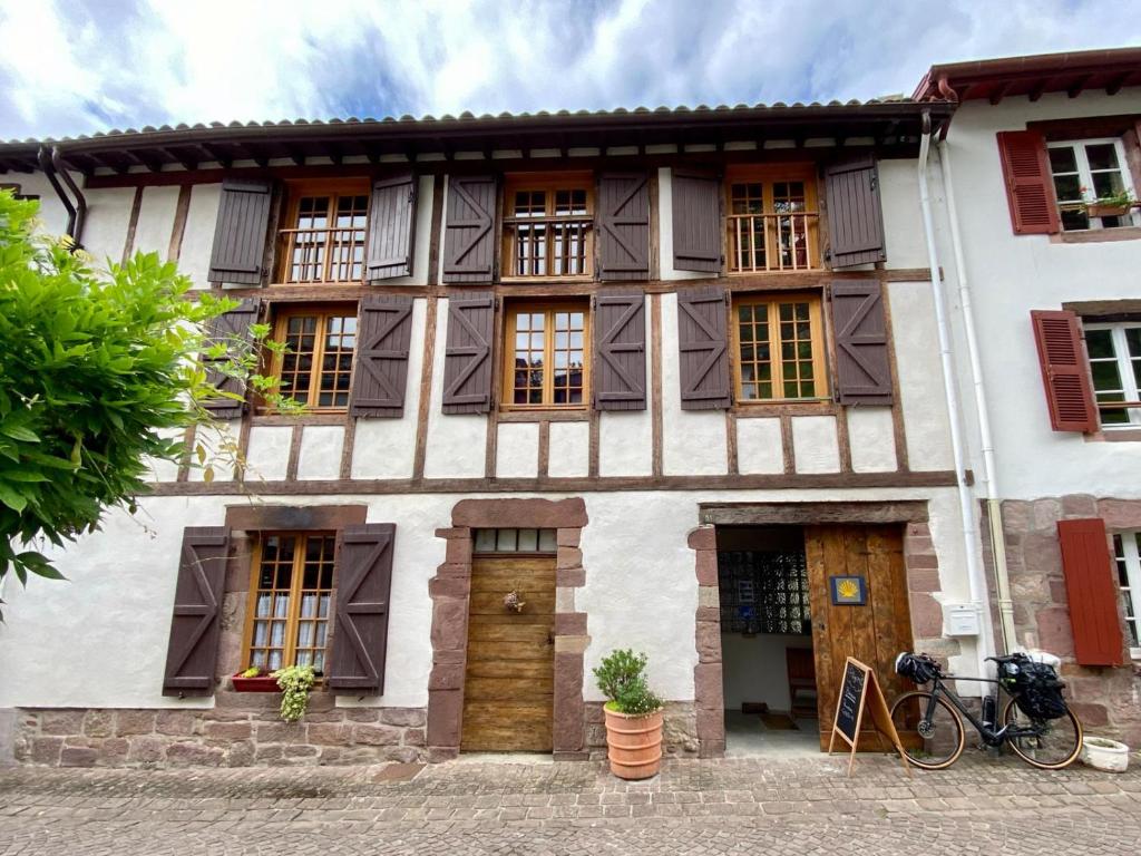 an old house with windows and a bike parked in front of it at Gite de la Porte Saint Jacques: a hostel for pilgrims in Saint-Jean-Pied-de-Port