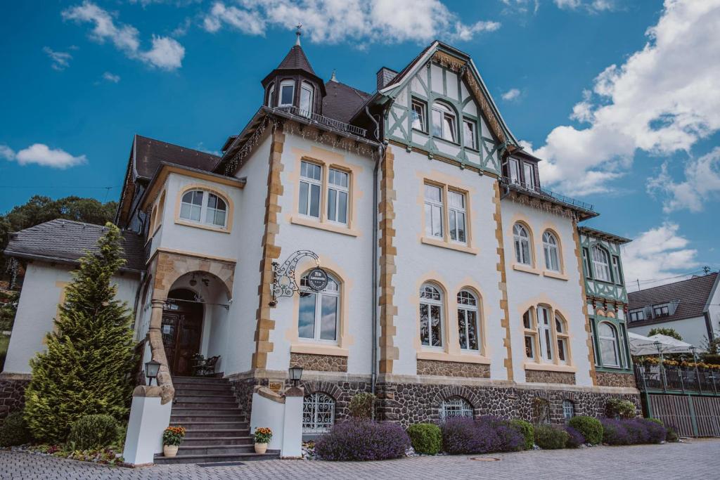 a large white house with a turret at Alte Landratsvilla Hotel Bender in Westerburg