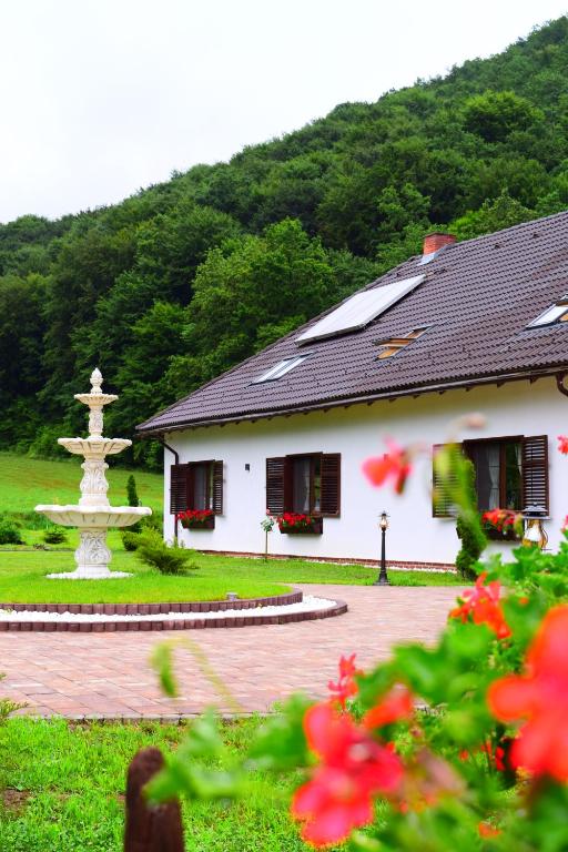 a white building with a fountain in a yard at Domeniul Poiana Ursului in Dumbrăveni
